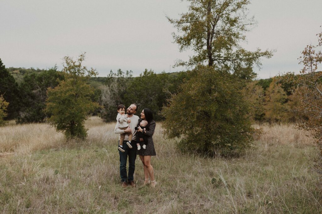 Family standing together and looking at each other during their Texas hill country family photos.