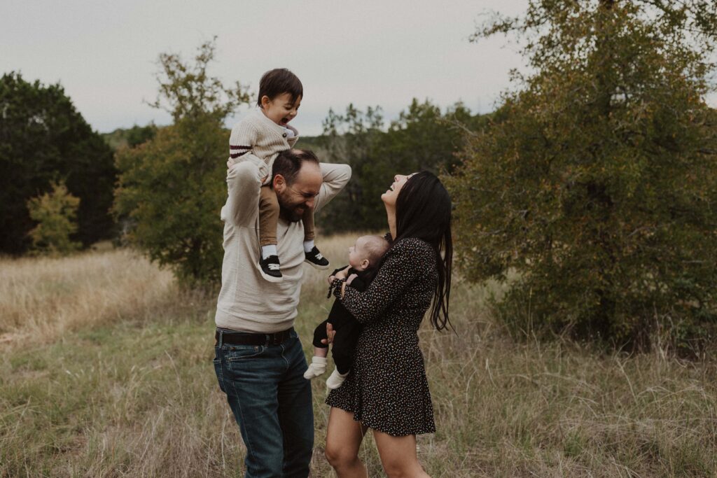 Dad giving toddler a ride on his shoulders during their Texas hill country family photos.