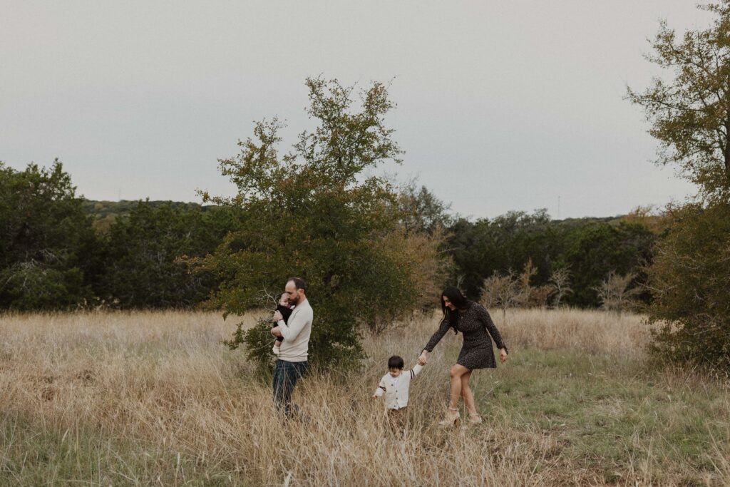 Family walking through tall grass together during their Texas hill country family photos.