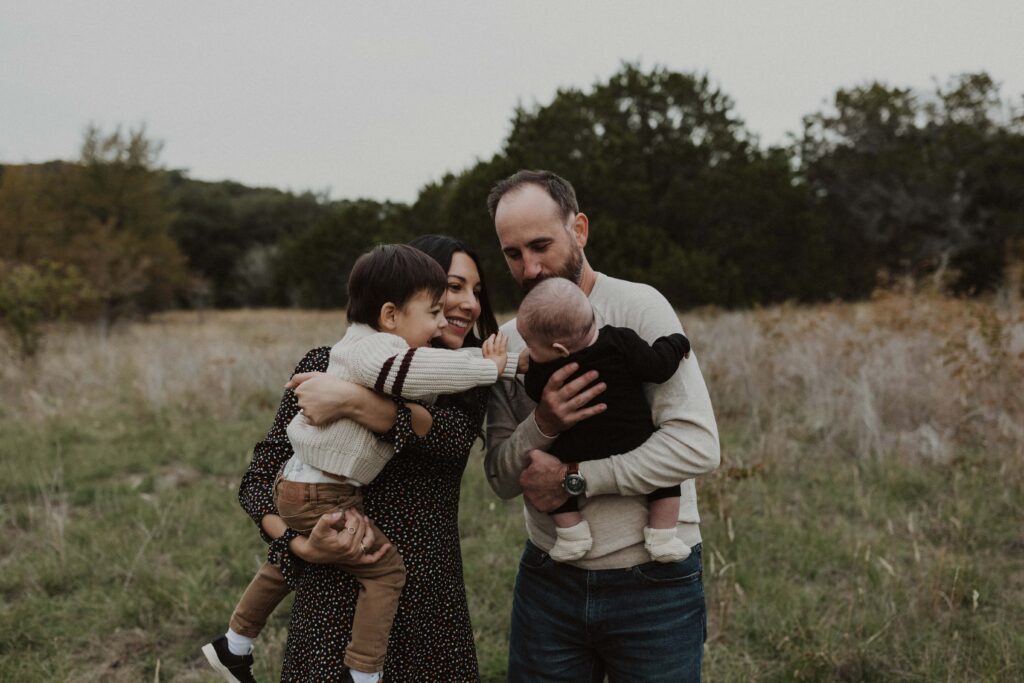 Big brother reaching out for his baby brother during their Texas hill country family photos.