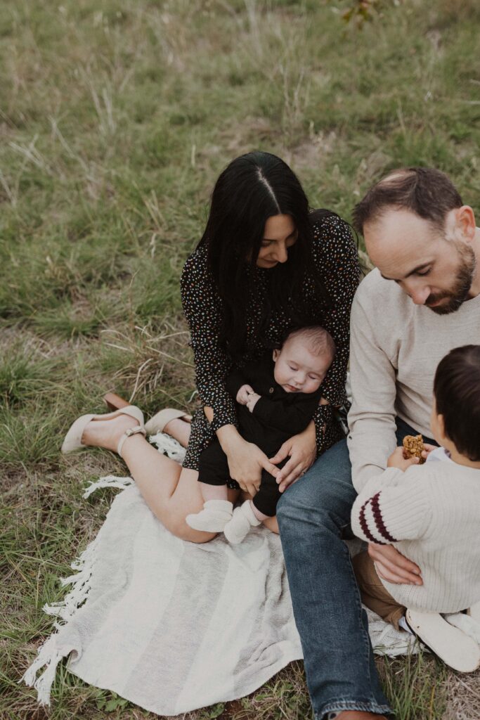 Family sitting together in tall grass during their Texas hill country family photos.