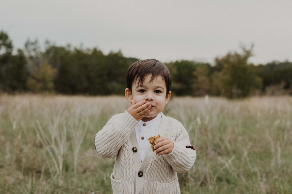 Little boy eating a granola bar during their Texas hill country family photos.