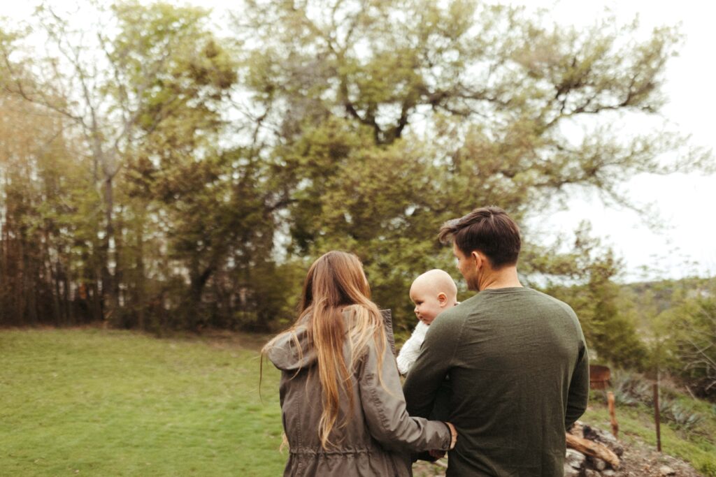 Mom Dad and Baby walking around their backyard during their family photo session in Austin Texas.